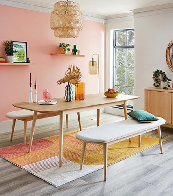 oak dining set on bright rug next to a pink wall