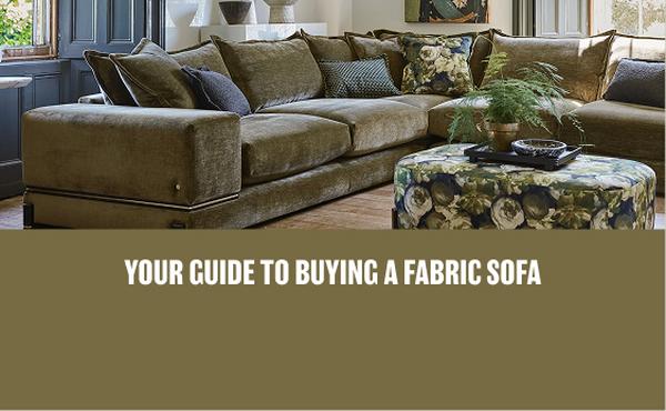 A dark green corner sofa with gold trim and french seam cushions with floral scatters