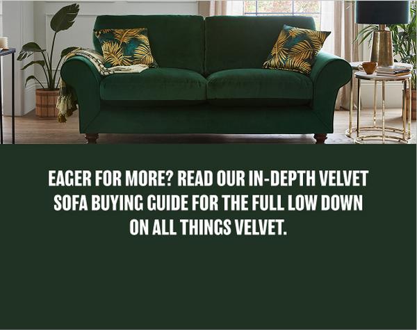 A dark green velvet sofa with gold and green cushions