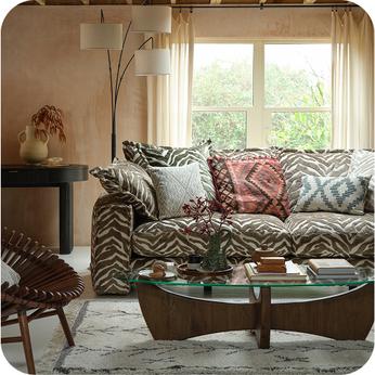 Zebra print sofa with patterned scatter cushions with a dark wood coffee table and accent chair