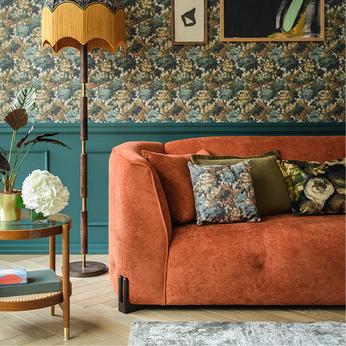 orange sofa in a green panelled room with floral wallpaper