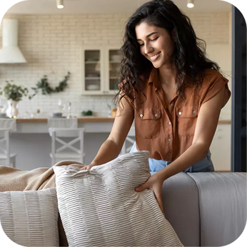 person adjusting a pillow on a sofa