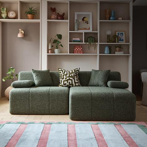 green compressed sofa with shelving unit on back wall