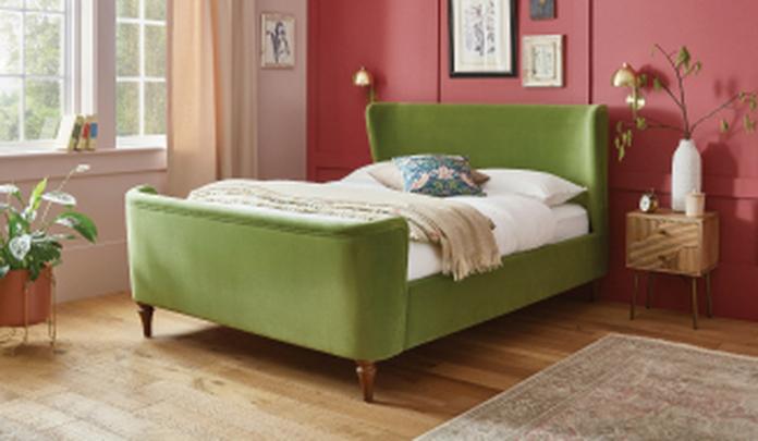 Green bed on wooden floor with pink walls