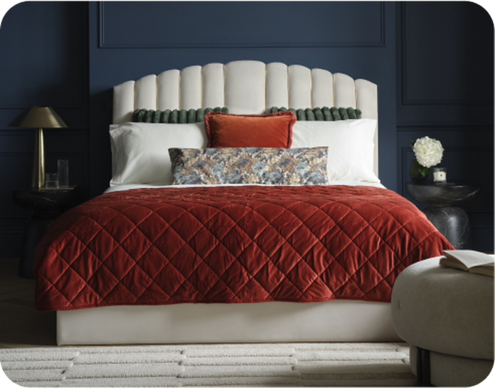 White padded be against a navy blue wall finished with white and red bedding