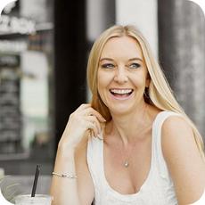 image a person with ling blonde hair and white vest smiling