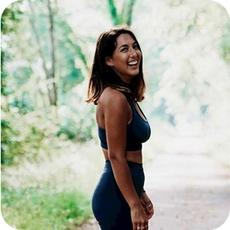 image a person with long dark hair in yoga clothing stood in a wooded setting