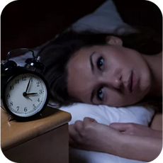 person laying in bed staring at the clock