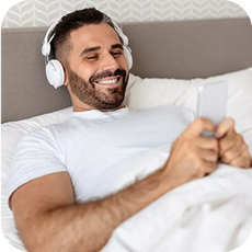 A person laying in bed with headphones on smiling