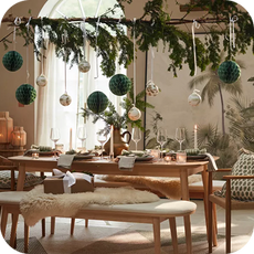 wooden dining table surrounded by chairs with leafy decorations