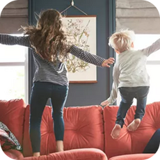 Children jumping on a red sofa