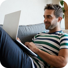 person laying on sofa with a laptop on their legs