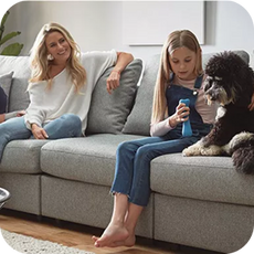 parent and child on grey sofa with a black dog