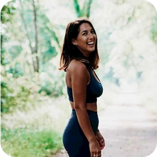 image a person with long dark hair in yoga clothing stood in a wooded setting