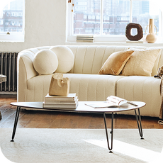 a cream curved sofa with ball-shaped cushions
