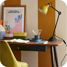 A walnut effect desk in front of a cream and orange striped wall