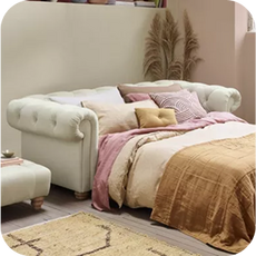 A small cream chesterfield sofa bed converted into a bed