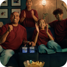 a family watching a game and celebrating on the sofa