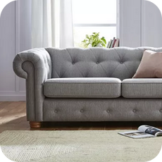 A large grey chesterfield sofa with pink scatter cushion