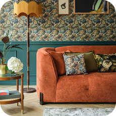 an orange curved sofa next to an old fashioned floor lamp
