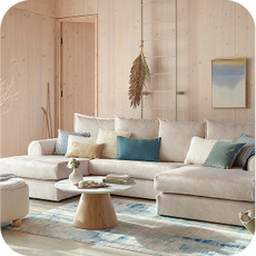 a large U-shaped cream sofa in a wooden coastal-themed room