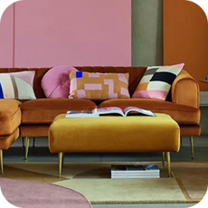 an orange velvet retro style sofa in a pink and orange room