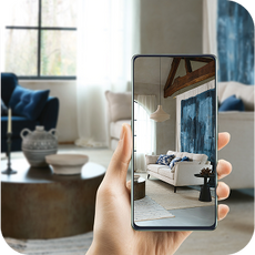 a hand holding a phone taking a picture of a white sofa