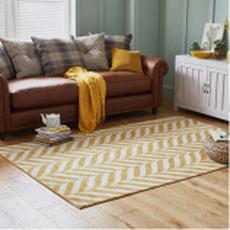 yellow and white pattern rug on an oak floor in front of a brown sofa