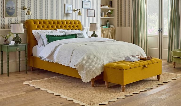 Mustard yellow bed with rolled headboard in a striped bedroom