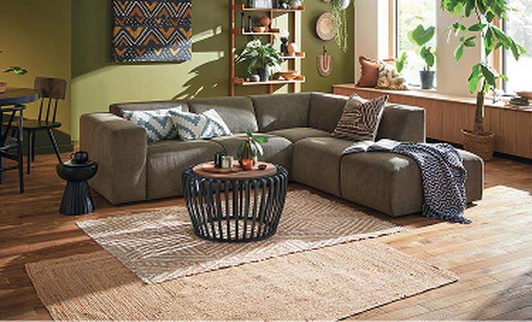 olive green corner sofa with wooden accessories and plants