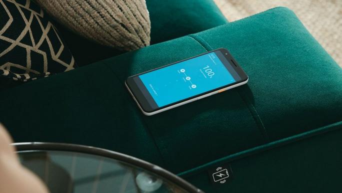 Close up of a velvet green sofa charging up a mobile phone