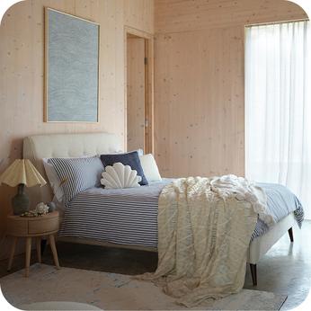 White bedframe in a room with light pine coloured walls