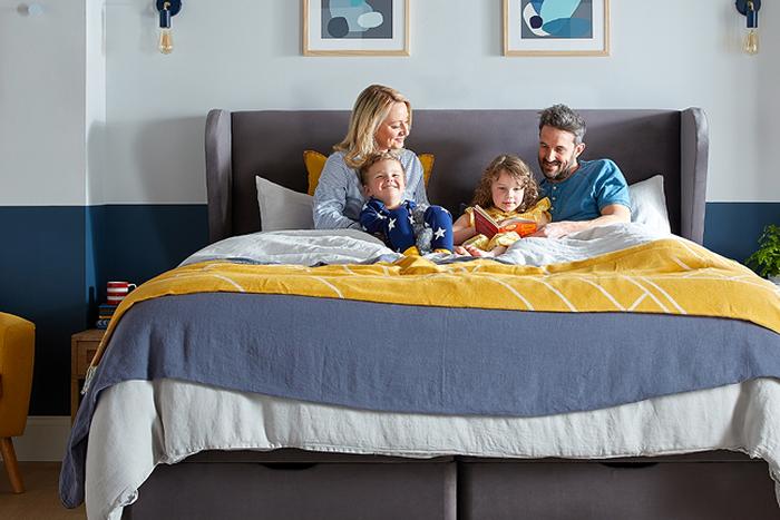 a family of 4 all sat in bed in there pyjamas