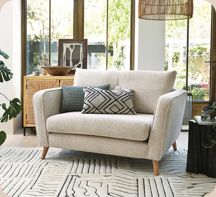 Cream cuddler sofa with green accents and neutral background