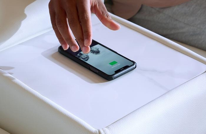 close up of a hand placing a phone on to a wireless charging pad