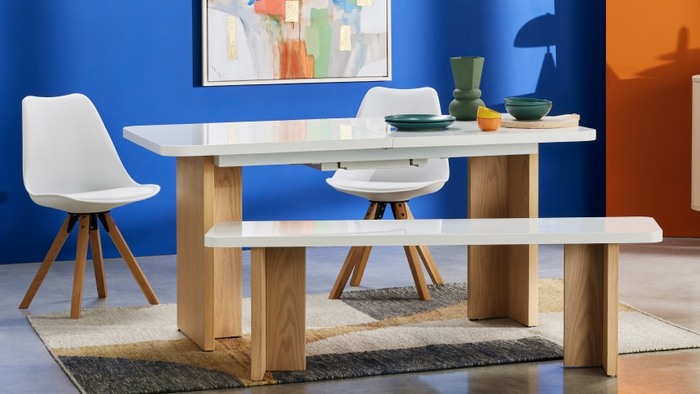 white dining bench under a white dining table with 2 white plastic chairs