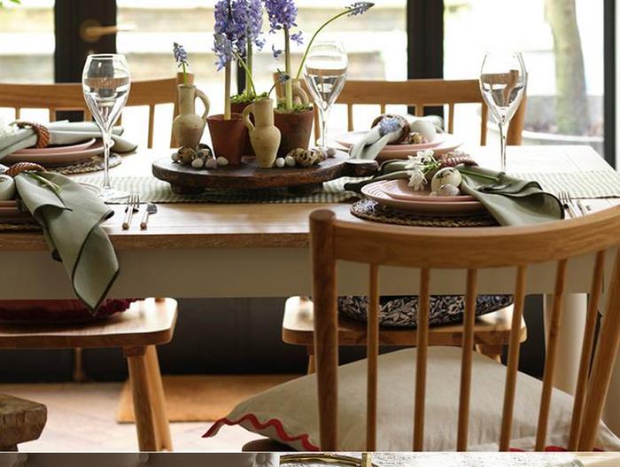 Wooden dining set with sage green napkins, wine glasses and pastel pink place settings 