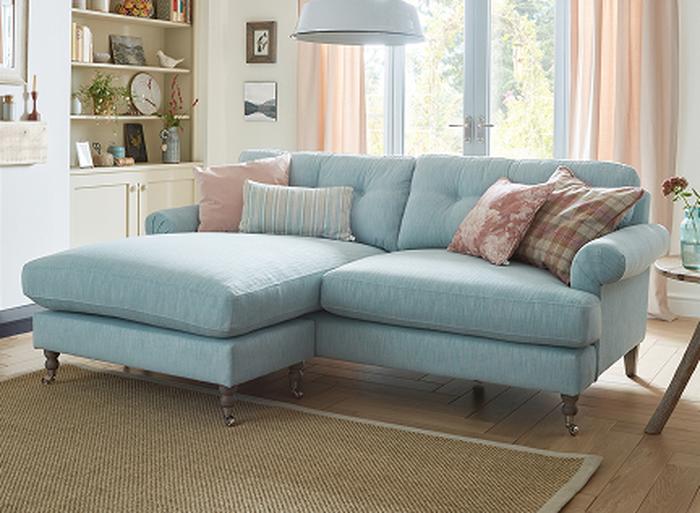 A light blue sofa in front of doors with blush curtains