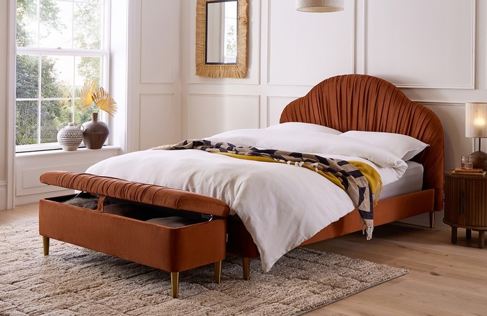 Rust coloured bedframe in a white room