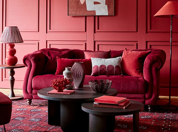 A velvet red sofa with red backdrop