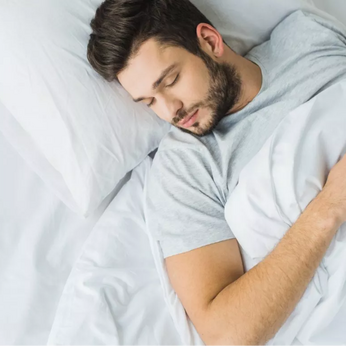 Man sleeping on his back in a white bed