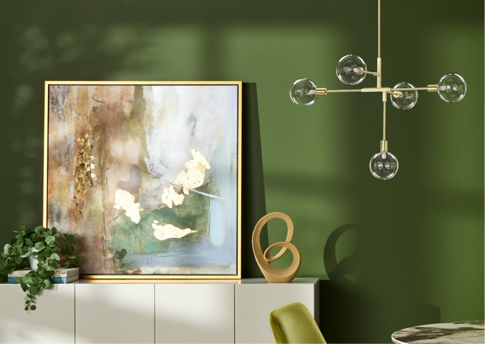 A modern living space featuring a large abstract painting, a stylish gold ceiling light against a green wall.