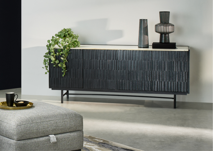 A black sideboard with marble top finished with black vases and a hanging plant