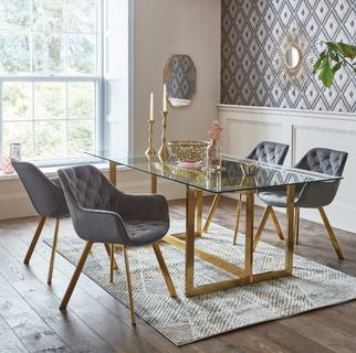 modern dining table and chair set, with a glass table top with gold legs and grey velvet dining chairs