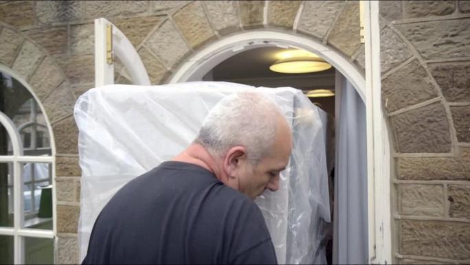 A man delivering a new sofa into a home