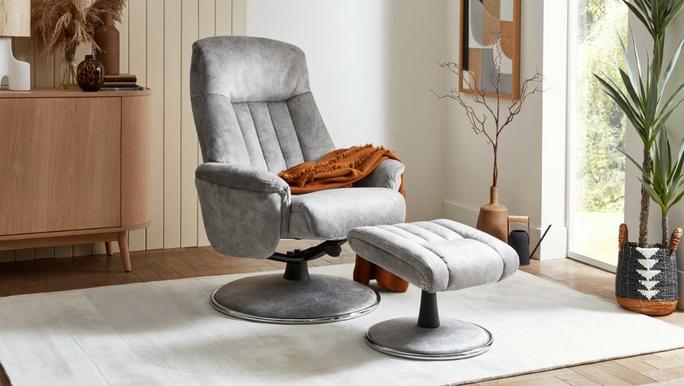 Light grey swivel chair with matching footstool finished with an orange throw and white rug