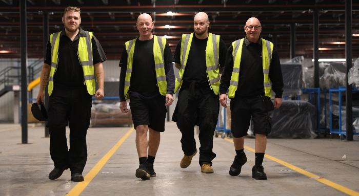 Four men walking through a warehouse