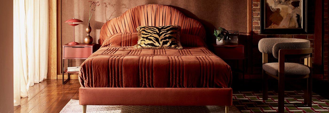 Terracotta upholstered bed with matching bedding in a styled bedroom