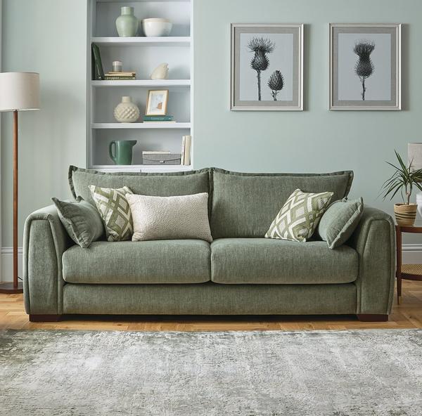 Sage green sofa with scatter cushions and rug infront