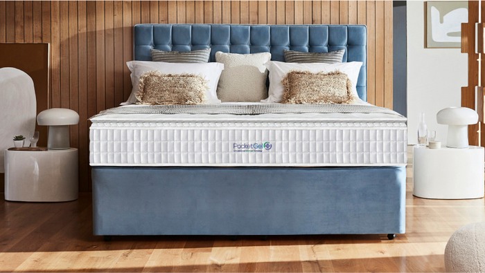blue divan bed with a blue tufted headboard, featuring plush pillows and a white mattress